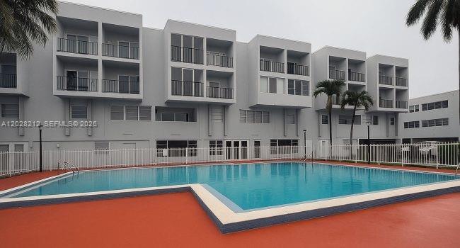 A multi-story apartment building with balconies overlooks a rectangular swimming pool with a red deck — 1555 W 44th Pl # 203, Hialeah FL 33012, HIALEAH, FL