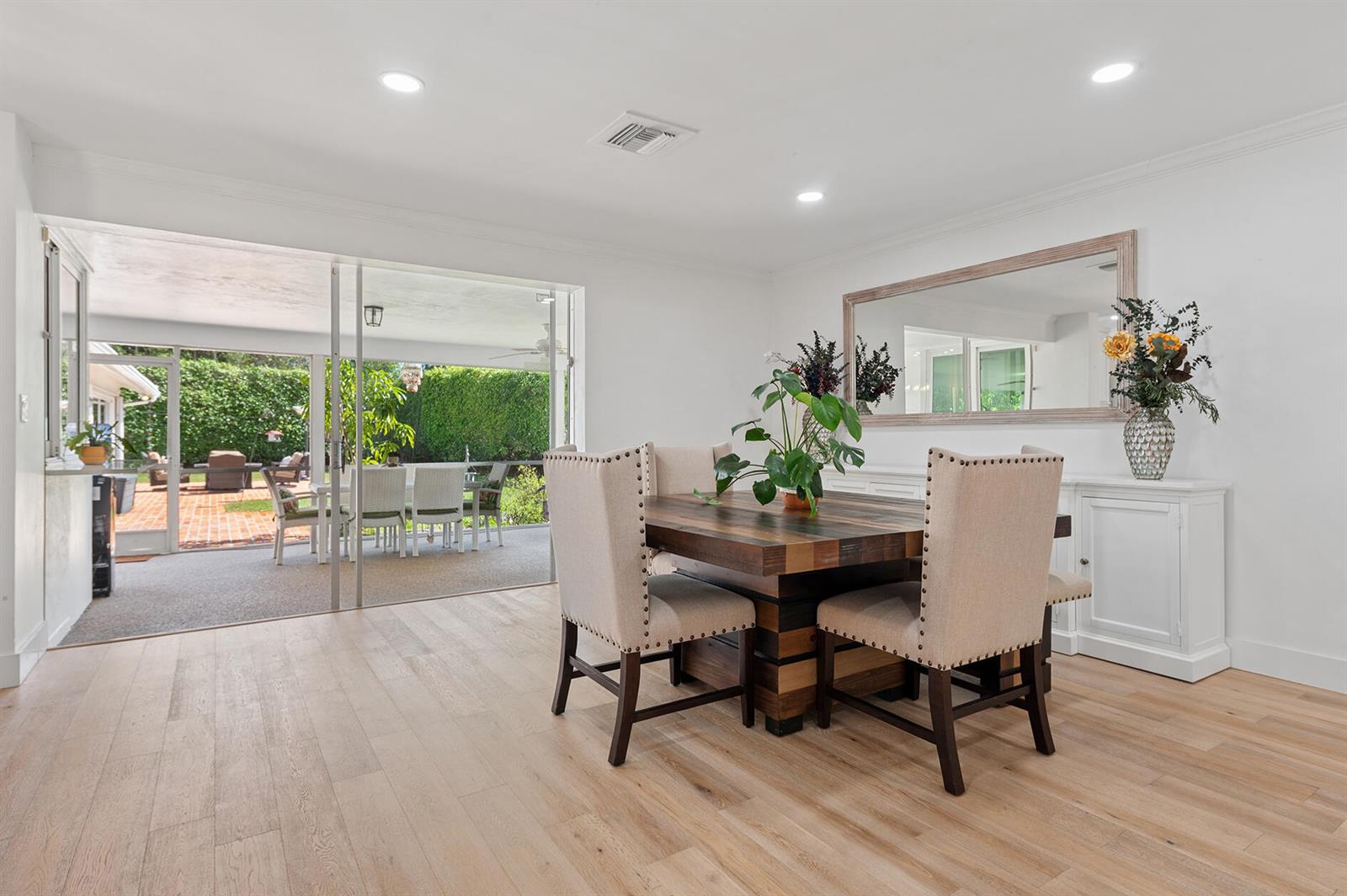 A dining room with a wooden table, upholstered chairs, and sliding doors to a patio — 2001 NW 1st Avenue, Delray Beach FL 33444, DELRAY BEACH, FL