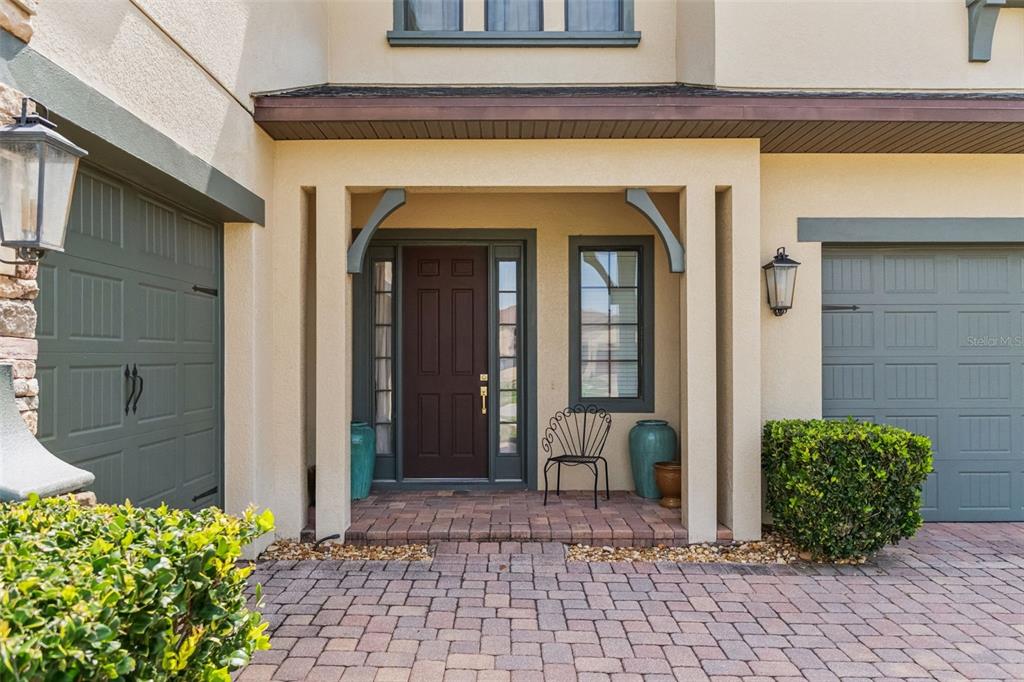 A front entryway features a dark door, a small metal chair, and two garage doors — 4117 FOXHOUND DRIVE, CLERMONT, FL