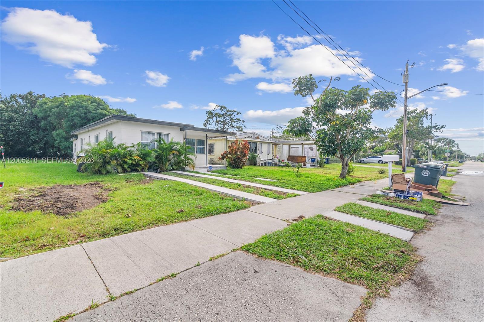 A single-story house with a concrete driveway and a green lawn under a blue sky — 1408 N 23rd St # 0, Fort Pierce FL 34950, FORT PIERCE, FL