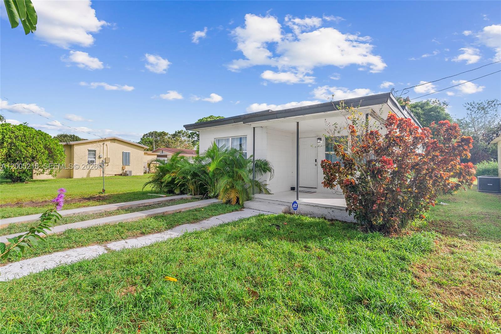 A white single-story house with a front porch and a lawn under a blue sky — 1408 N 23rd St # 0, Fort Pierce FL 34950, FORT PIERCE, FL