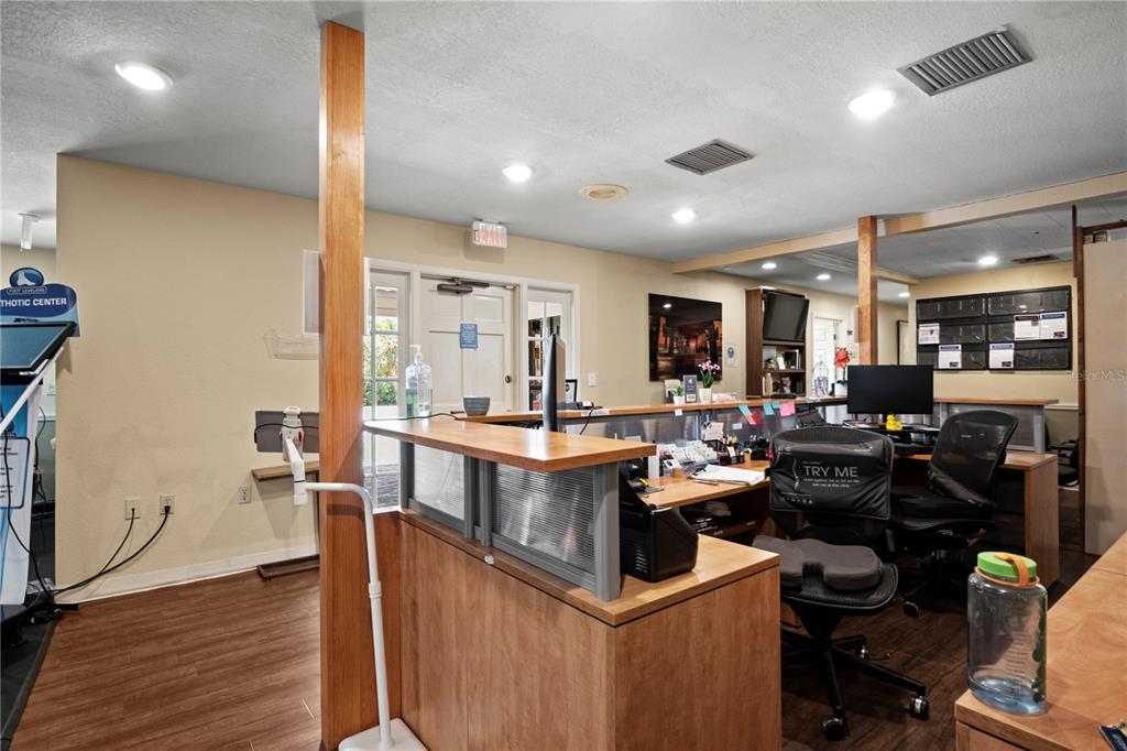 A reception area features a wooden desk, office chairs, and a doorway with an exit sign — 1700 DR MARTIN LUTHER KING JR STREET N UNIT A, ST PETERSBURG, FL