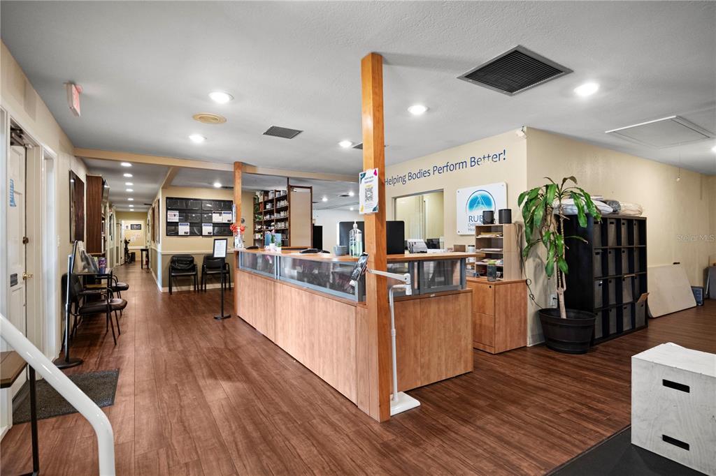 A reception area features a wooden desk, wood-look flooring, and a hallway leading to offices — 1700 DR MARTIN LUTHER KING JR STREET N UNIT A, ST PETERSBURG, FL