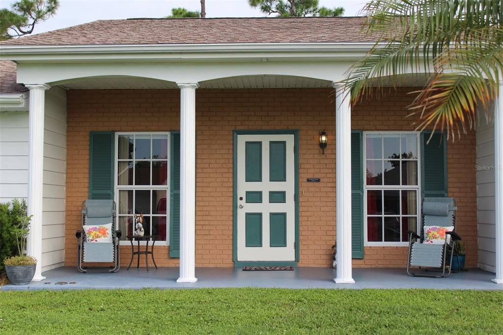 A front porch with brick walls, two windows with green shutters, and a central door — 2320 ALTON ROAD, PORT CHARLOTTE, FL