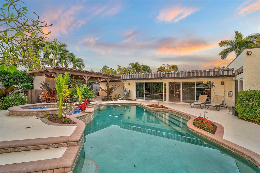 A backyard swimming pool with a hot tub and a covered patio at sunset — 4508 WOODSIDE ROAD, SARASOTA, FL
