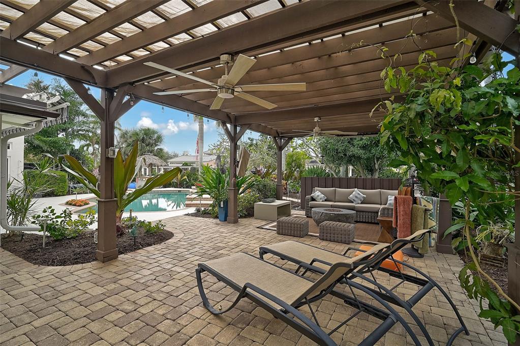 A covered outdoor patio features a pergola, ceiling fans, lounge chairs, and a seating area — 4508 WOODSIDE ROAD, SARASOTA, FL