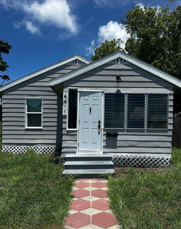 A gray, single-story house with a white front door and a hexagonal paver walkway — 4411 16TH AVENUE S, ST PETERSBURG, FL