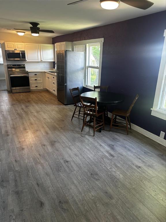 A kitchen with white cabinets, stainless steel appliances, and a small dining table on wood-look flooring — 4411 16TH AVENUE S, ST PETERSBURG, FL