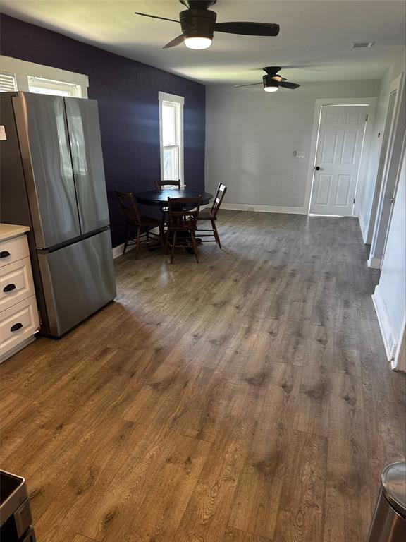 A kitchen and dining area featuring wood-look flooring, a stainless refrigerator, and a dark accent wall — 4411 16TH AVENUE S, ST PETERSBURG, FL