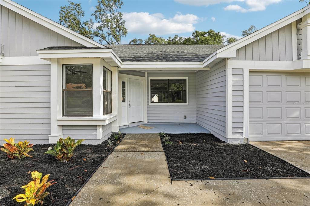 A gray house exterior features a front walkway, a bay window, and a garage — 7019 KENSINGTON HIGH BOULEVARD, ORLANDO, FL