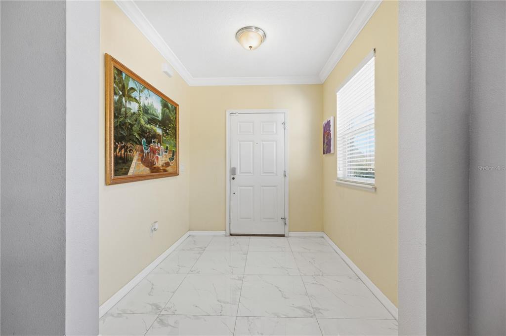 An entryway features white marble-look tile flooring, pale yellow walls, and a white front door — 643 WASHINGTON WAY, HAINES CITY, FL