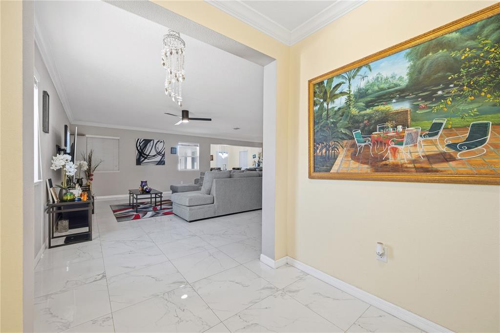 A view from a tiled hallway into a living room with a large gray sectional — 643 WASHINGTON WAY, HAINES CITY, FL