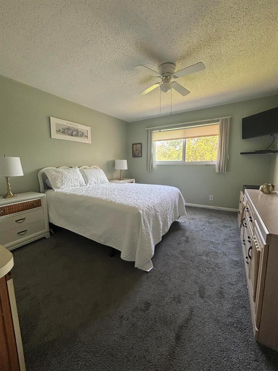 A bedroom features a bed with white bedding, two nightstands, a dresser, and a ceiling fan — 725 Lori Drive # 203, Palm Springs FL 33461, PALM SPRINGS, FL