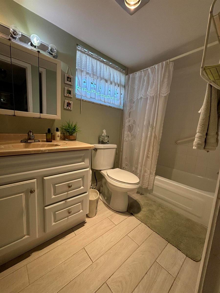 A bathroom features a vanity with a beige countertop, a toilet, and a shower-tub combination — 725 Lori Drive # 203, Palm Springs FL 33461, PALM SPRINGS, FL