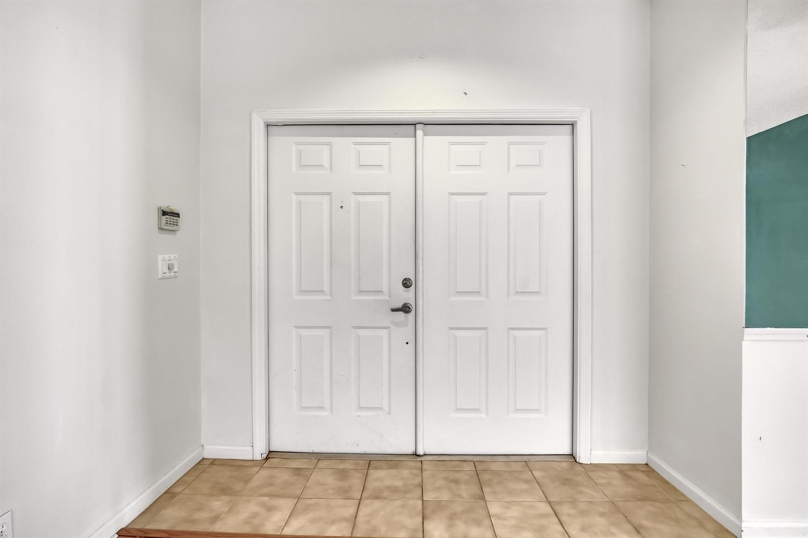 A white double front door with a tiled floor in an interior entryway — 180 Caribe Court, FL 33413, FL