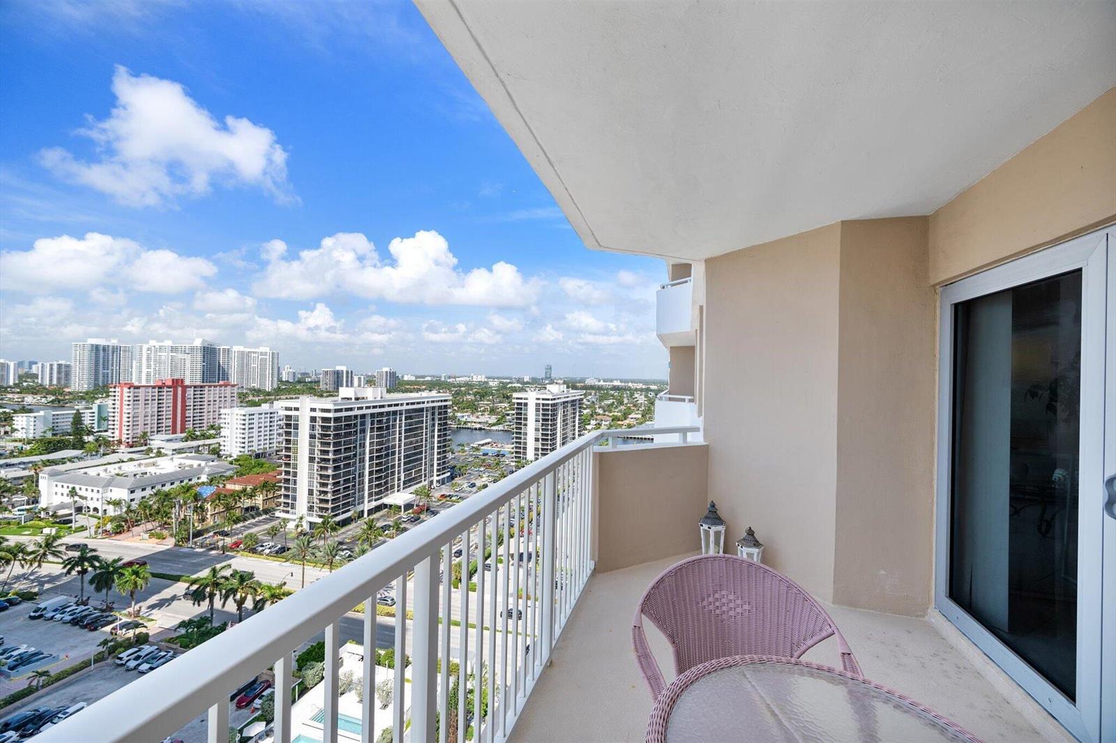 A high-rise balcony with a white railing overlooks a city skyline and a parking lot — 1980 S Ocean Drive # 19a, Hallandale Beach FL 33009, HALLANDALE BEACH, FL