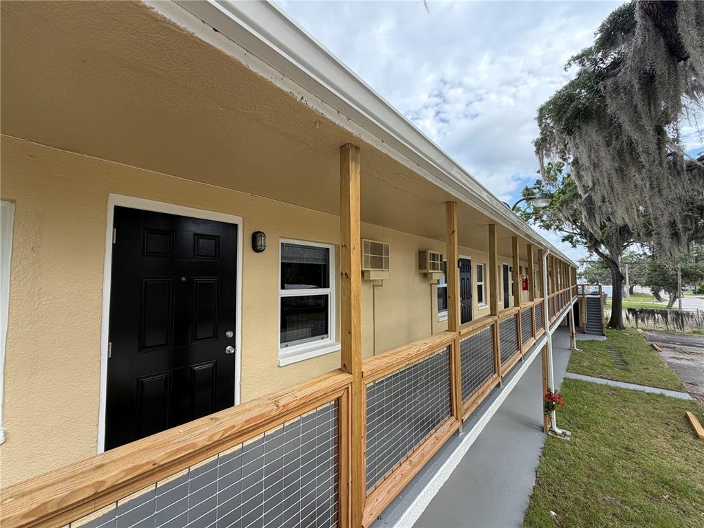 An exterior view of a motel-style building with a wooden walkway and black doors — 419 GRAPEFRUIT AVENUE UNIT 7A, SEBRING, FL