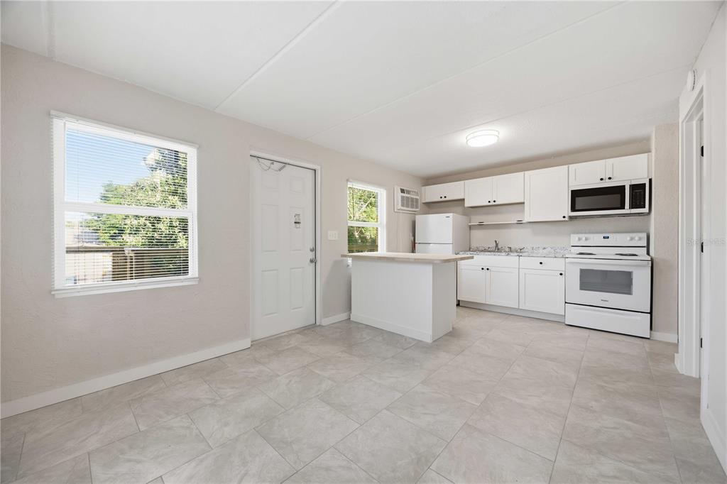 A kitchen and dining area with white cabinets, white appliances, and light-colored tile flooring — 419 GRAPEFRUIT AVENUE UNIT 7A, SEBRING, FL