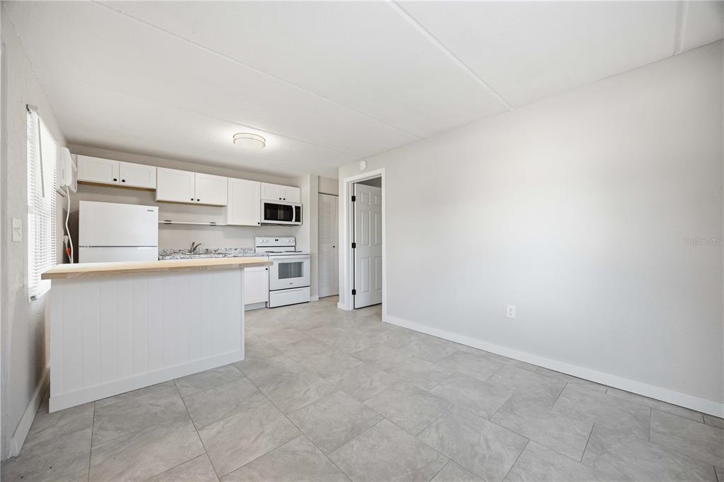 A kitchen with white cabinets and appliances features a breakfast bar and tile flooring — 419 GRAPEFRUIT AVENUE UNIT 7A, SEBRING, FL