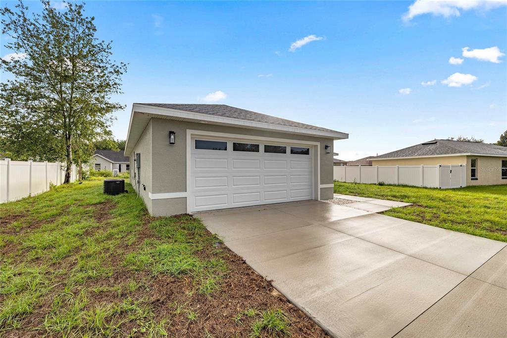 A detached garage with a white door and concrete driveway sits on a grassy lot — 181 PINE COURSE, OCALA, FL