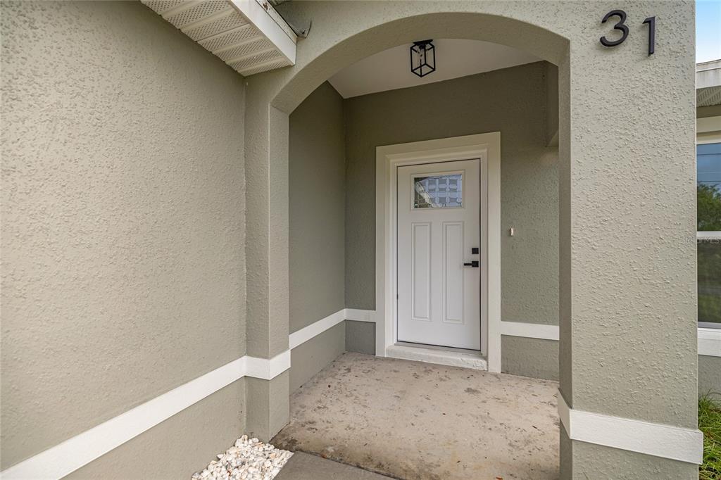 A covered entryway features a white front door with a window and the number 31 — 181 PINE COURSE, OCALA, FL