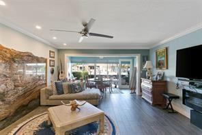 A living room features a large wood slab wall, a sofa, and a view of a patio — 1323 NE 28th Avenue # 126, Pompano Beach FL 33062, POMPANO BEACH, FL