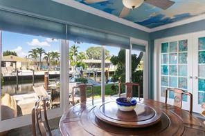 A dining room with a round wooden table, a cloud-painted ceiling, and large windows overlooking a canal — 1323 NE 28th Avenue # 126, Pompano Beach FL 33062, POMPANO BEACH, FL