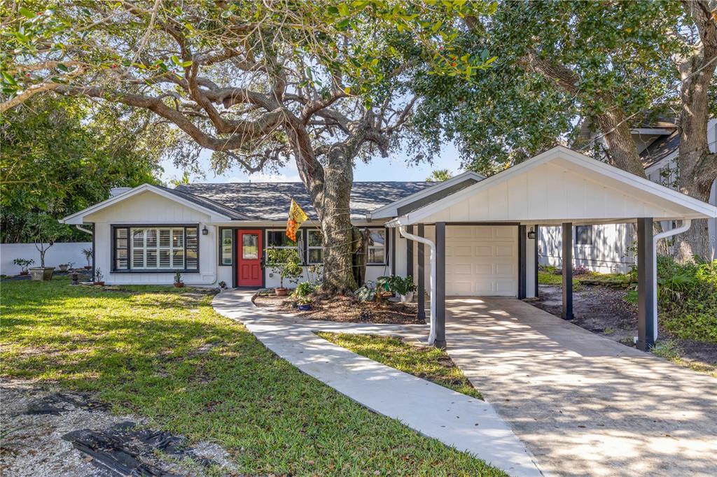 A single-story house with a white exterior, a red front door, and an attached carport — 4602 SAXON DRIVE, NEW SMYRNA BEACH, FL