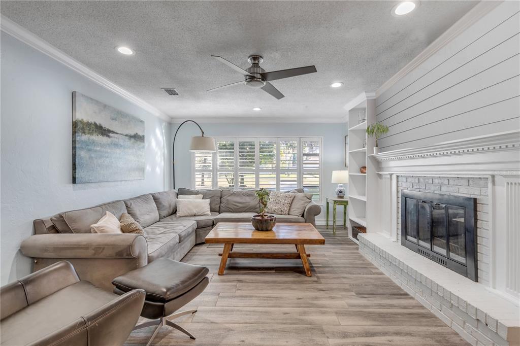 A living room features a sectional sofa, wooden coffee table, fireplace, and wood-look flooring — 4602 SAXON DRIVE, NEW SMYRNA BEACH, FL