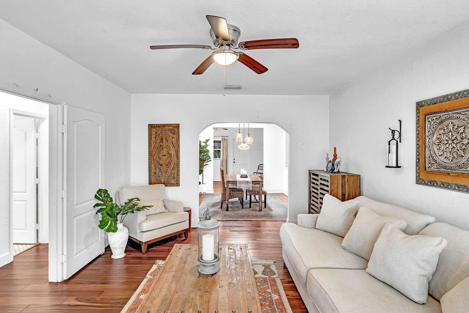 A living room with wood floors, a ceiling fan, and an arched doorway to a dining area — 784 NE 81st Street, Miami FL 33138, MIAMI, FL