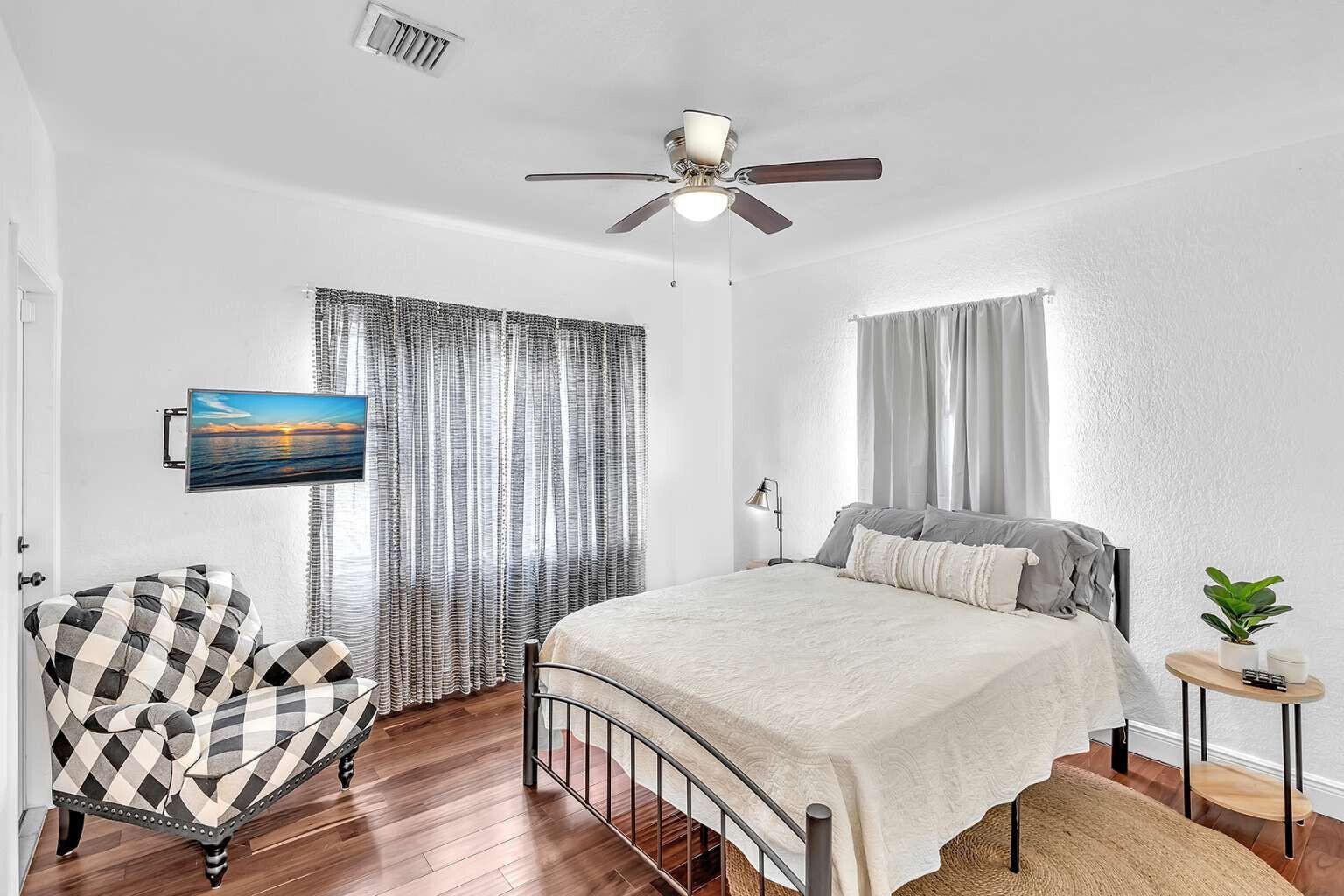 A bedroom features a metal bed frame, a plaid armchair, and wood-look flooring — 784 NE 81st Street, Miami FL 33138, MIAMI, FL