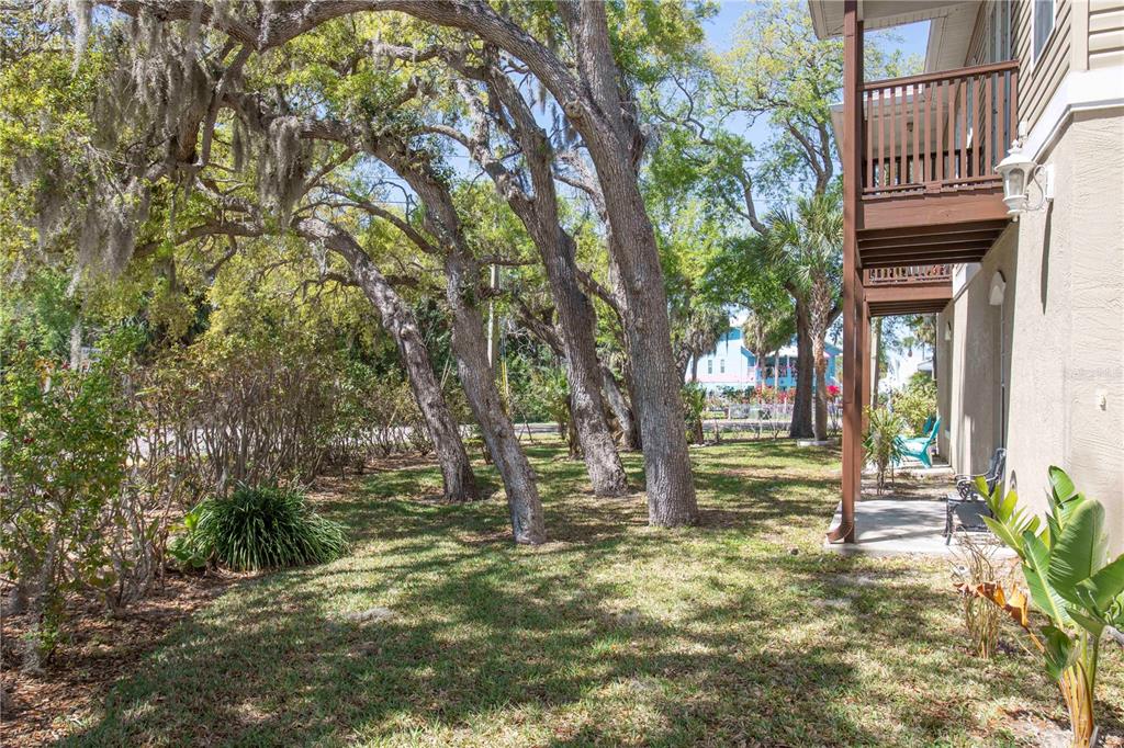 A grassy yard with large trees sits beside a two-story building with a wooden balcony — 4751 W MARINE PARKWAY UNIT 4751, NEW PORT RICHEY, FL