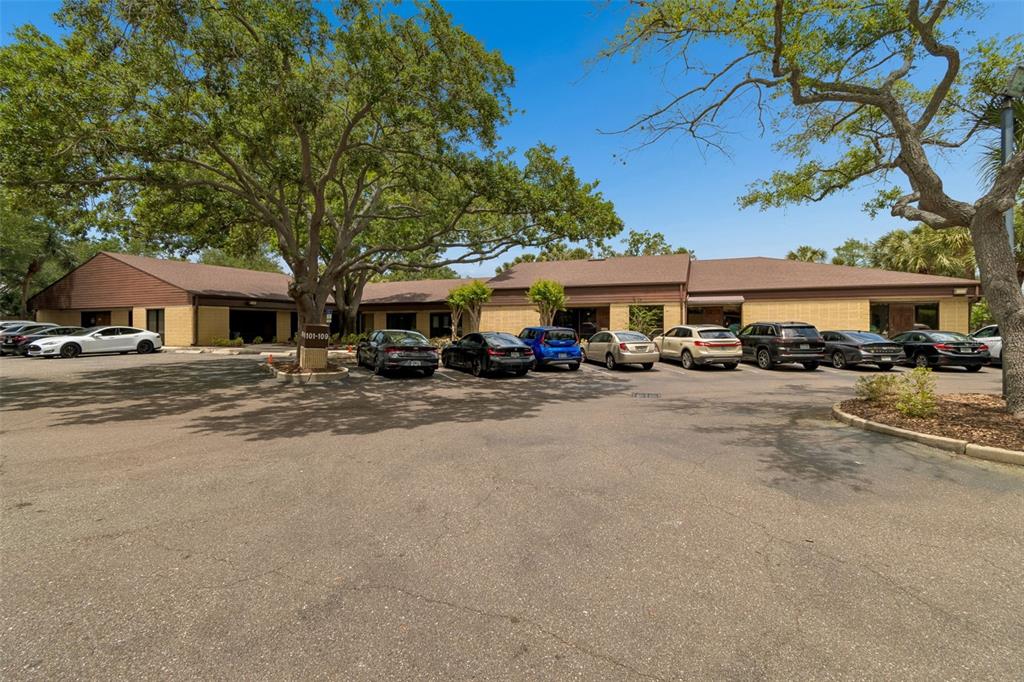 A single-story commercial building with a parking lot and large oak trees in front — 611 DRUID ROAD E UNIT 101-110, CLEARWATER, FL