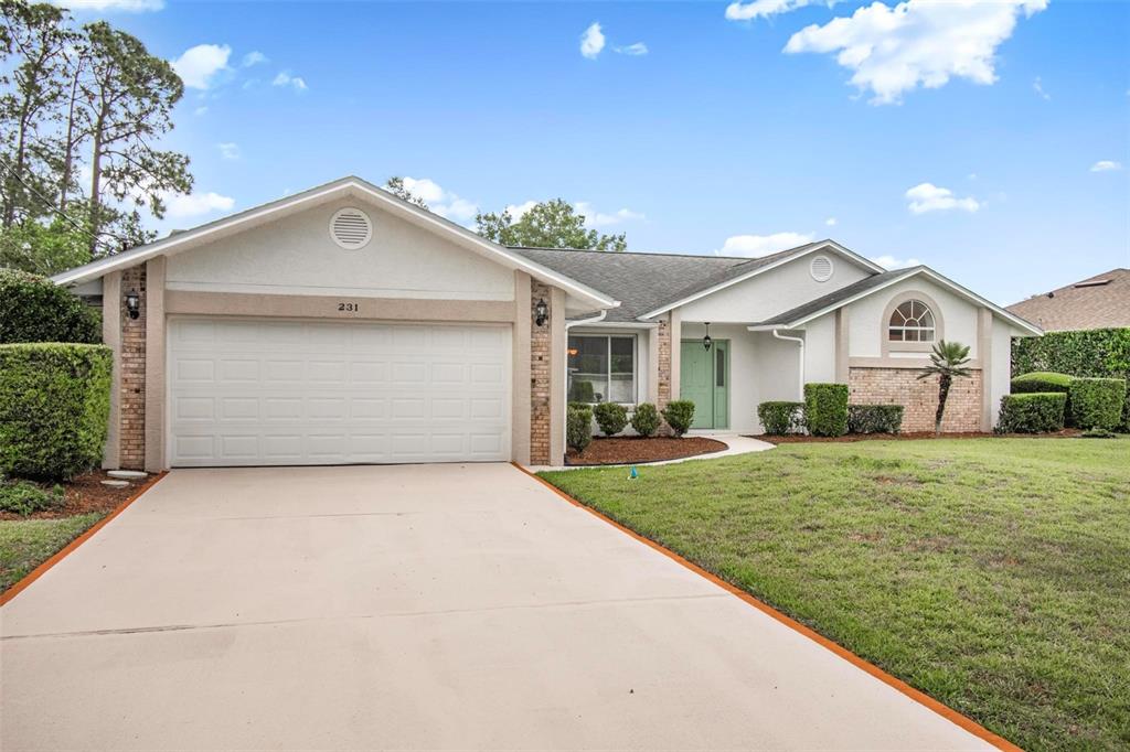 A single-story house with a white garage, light green front door, and a brick facade — 231 WELLINGTON DRIVE, PALM COAST, FL