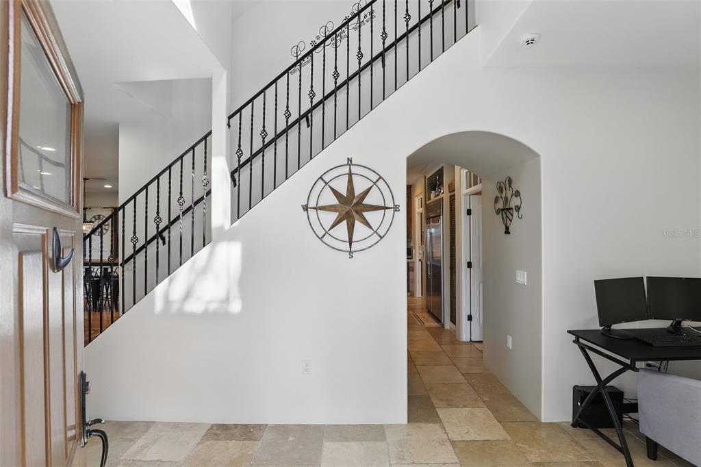 An entryway features a staircase with black iron railings, tile flooring, and a compass wall decoration — 106 VICTORIA STREET, MERRITT ISLAND, FL