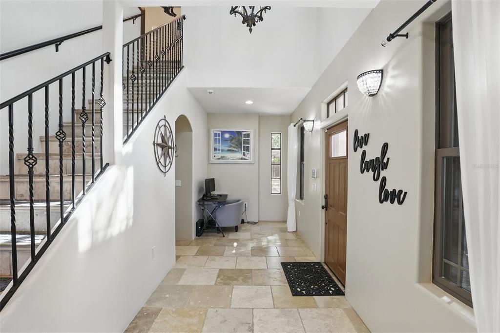 An entryway features a stone-tiled floor, a staircase with iron railings, and a wooden door — 106 VICTORIA STREET, MERRITT ISLAND, FL
