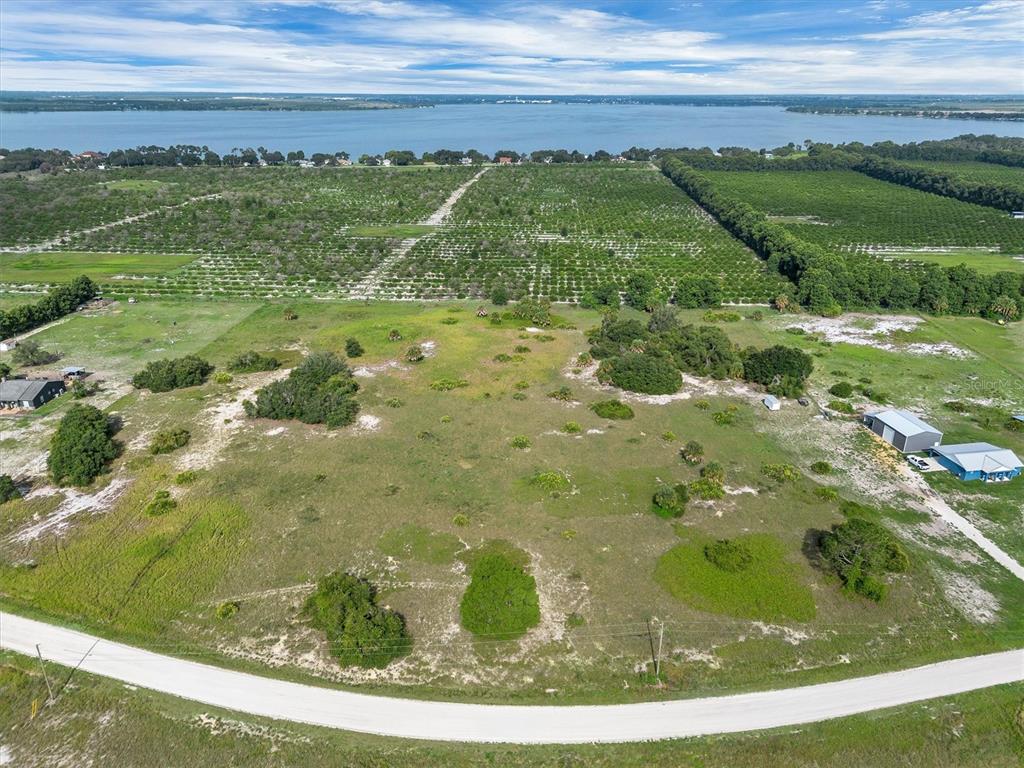 An aerial view shows a large, grassy vacant lot bordered by a road and citrus groves — 2478 OLD GROVE TRAIL, FROSTPROOF, FL