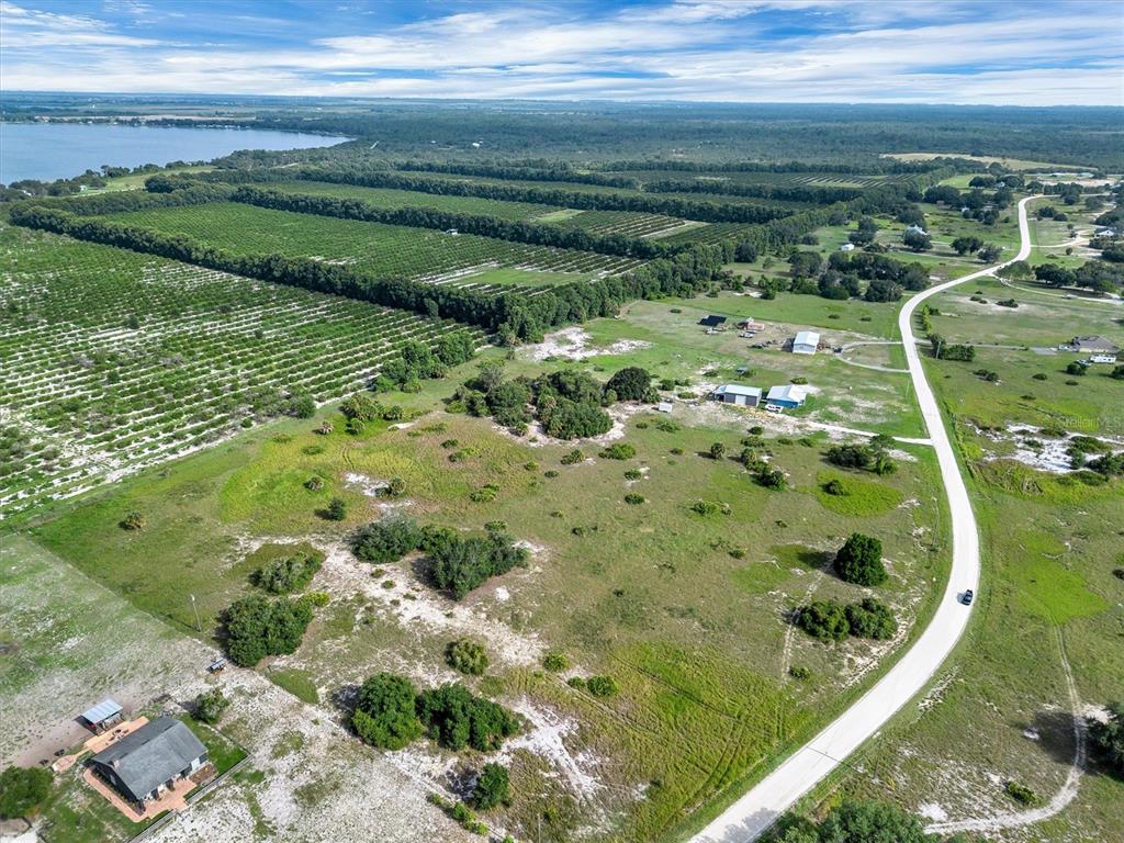 An aerial view shows a rural property with a house, outbuildings, and adjacent citrus groves — 2478 OLD GROVE TRAIL, FROSTPROOF, FL