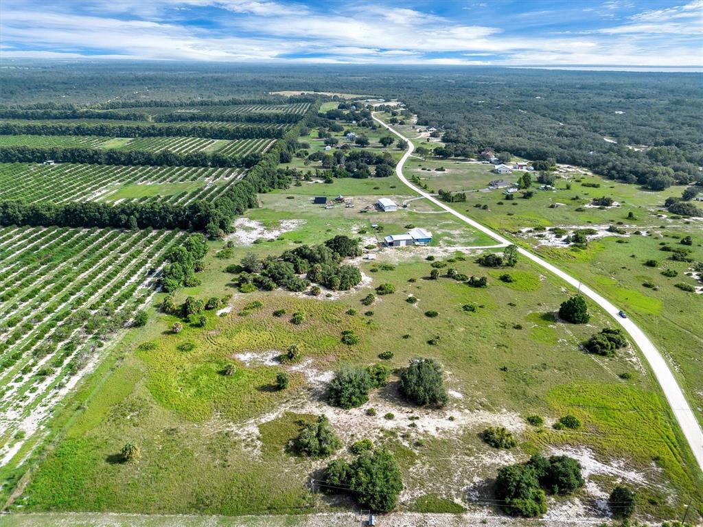An aerial view shows a rural property with citrus groves, open fields, and several buildings — 2478 OLD GROVE TRAIL, FROSTPROOF, FL