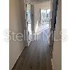 A narrow hallway with light-colored walls and dark wood-look flooring leads toward a bright room — 800 COVE CAY DRIVE UNIT 5D, CLEARWATER, FL