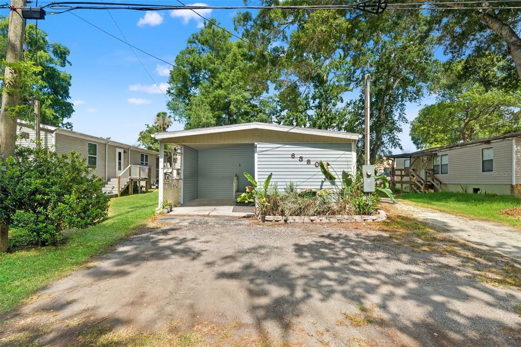 A light blue mobile home features a covered carport and a gravel driveway — 6380 RICHARD DRIVE, WEEKI WACHEE, FL