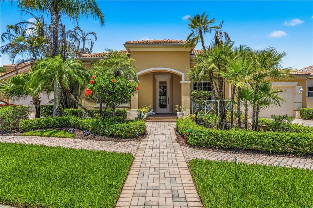 A single-story house with a paved walkway, palm trees, and manicured hedges in the front — VERO BEACH, FL