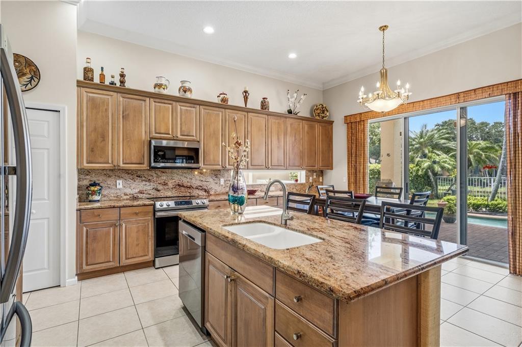 A kitchen with wood cabinets, granite countertops, a center island, and a sliding glass door — VERO BEACH, FL