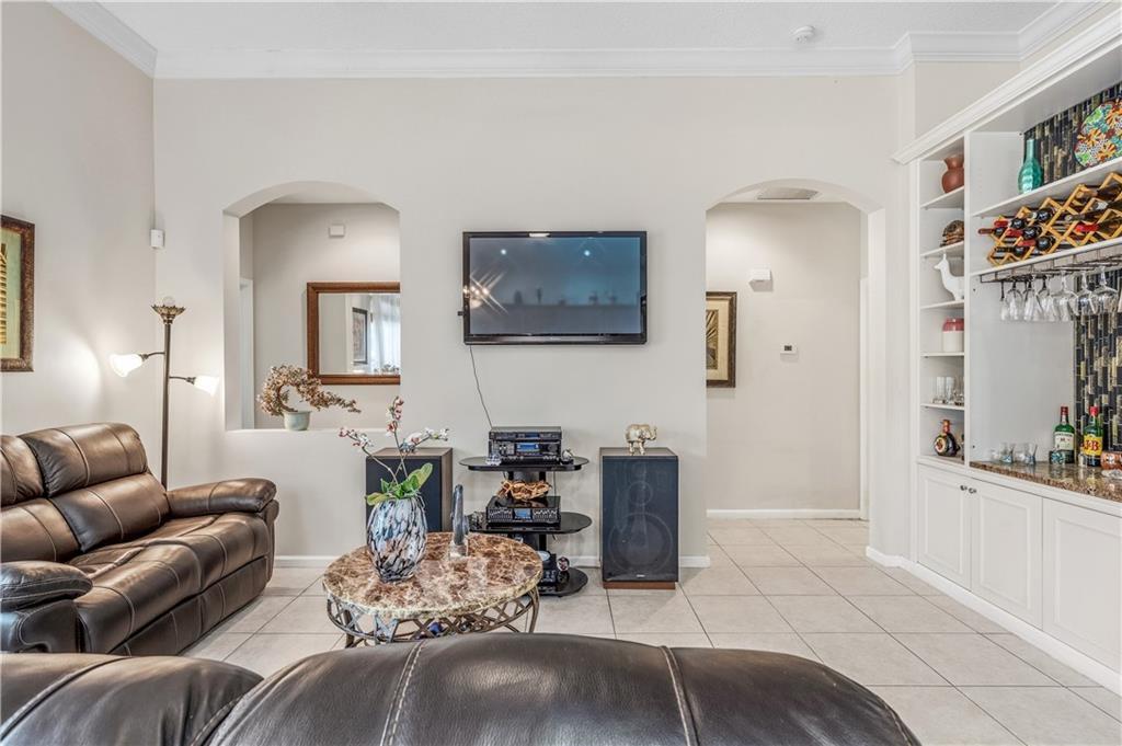 A living room features a leather sofa, a wall-mounted television, and a built-in bar area — VERO BEACH, FL