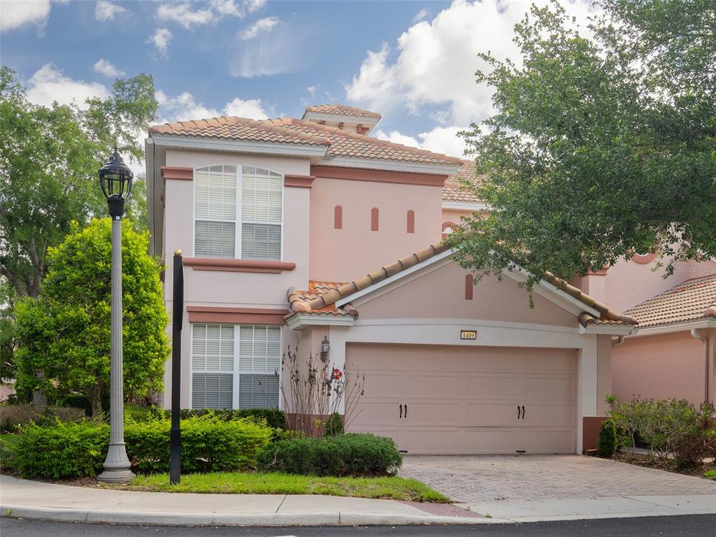 A two-story pink stucco house features a two-car garage and a tile roof — 1409 MILLEDGE LANE UNIT 1409, DAVENPORT, FL