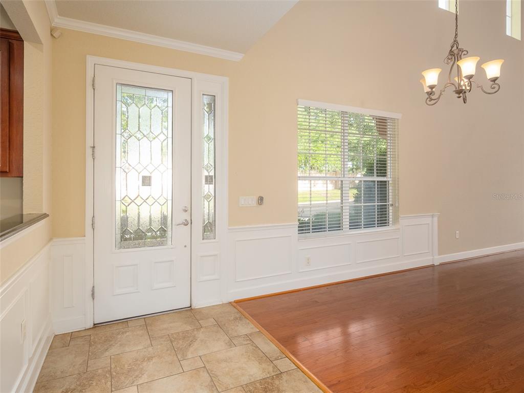 An entryway features a white front door with glass panels, tile flooring, and wainscoting — 1409 MILLEDGE LANE UNIT 1409, DAVENPORT, FL