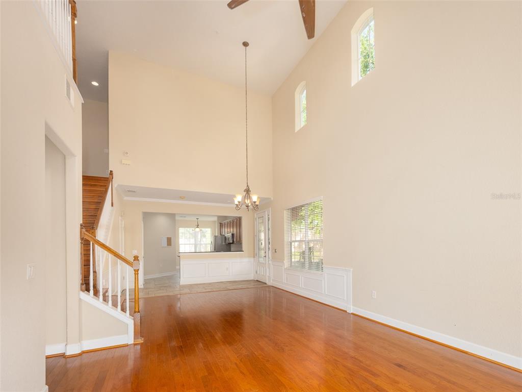 A living room with hardwood floors, a high ceiling, a chandelier, and a staircase — 1409 MILLEDGE LANE UNIT 1409, DAVENPORT, FL