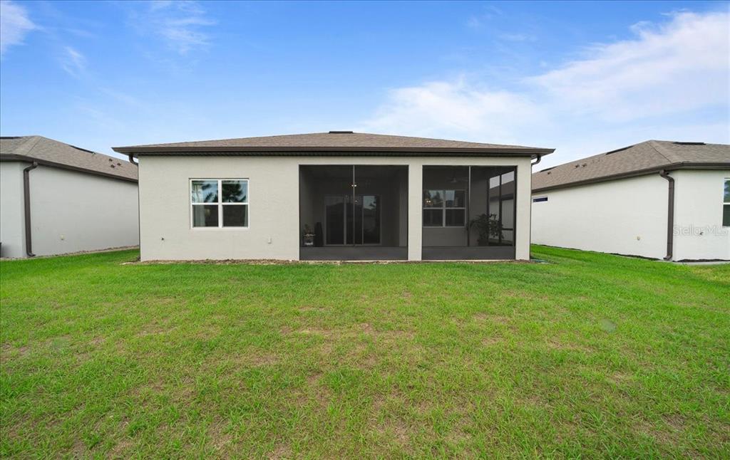 The rear exterior of a single-story house features a screened-in patio and a grassy yard — 8750 SW 59TH LANE ROAD, OCALA, FL
