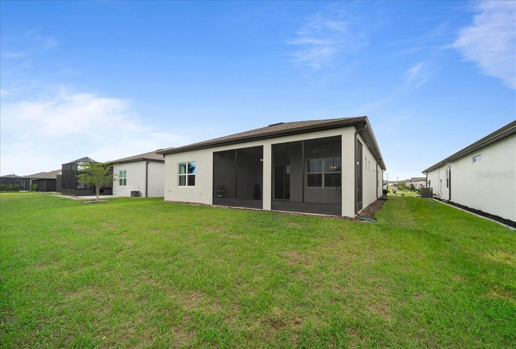 The exterior rear view of a house features a screened-in lanai and a grassy yard — 8750 SW 59TH LANE ROAD, OCALA, FL