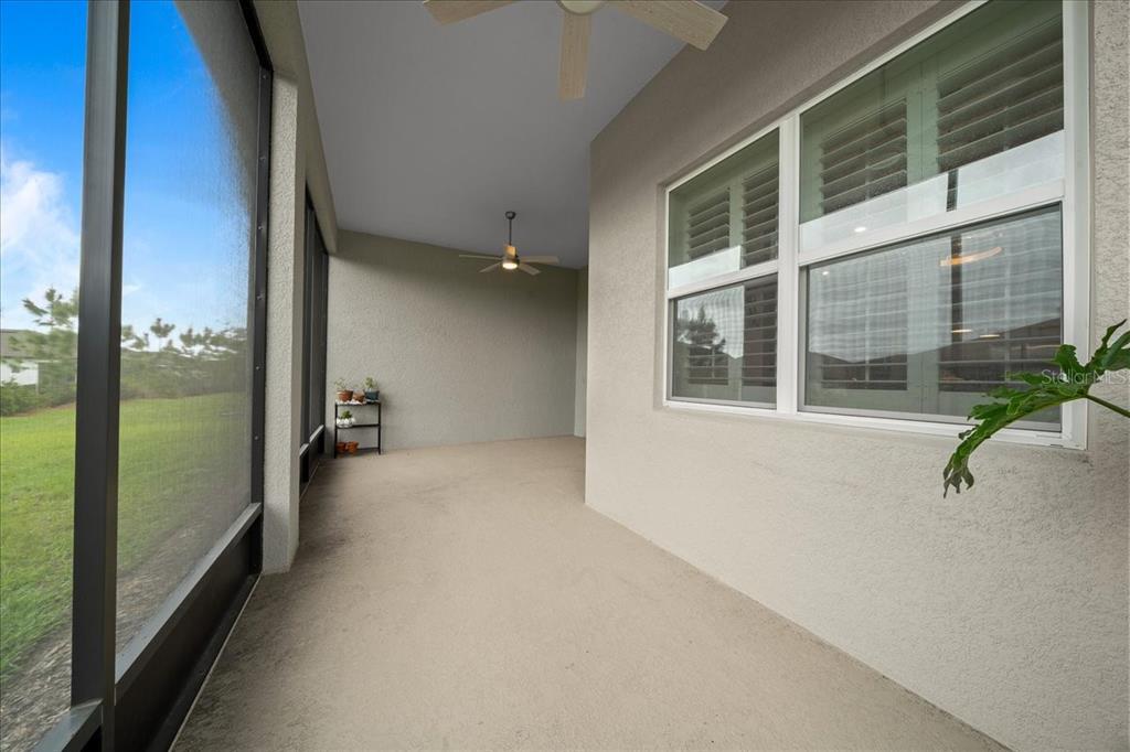 A covered patio features a concrete floor, a ceiling fan, and a screened-in wall — 8750 SW 59TH LANE ROAD, OCALA, FL